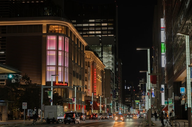Город Японии ночью с автомобилями и людьми