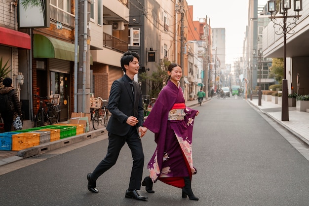 Free photo japanese couple celebrating coming of age day and posing outdoors in the city