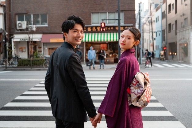 Foto gratuita coppia giapponese che festeggia il raggiungimento della maggiore età e posa all'aperto in città