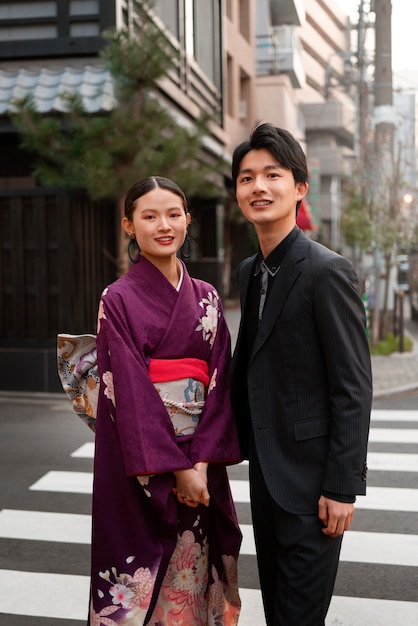 Free photo japanese couple celebrating coming of age day and posing outdoors in the city