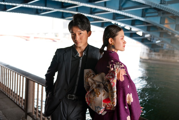 Free photo japanese couple posing at the bridge and celebrating coming of age day