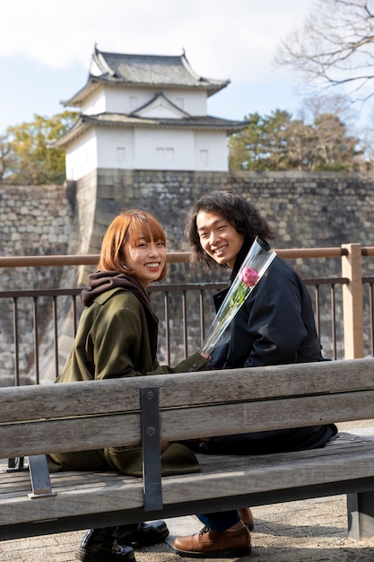 Японская пара позирует, сидя на скамейке на открытом воздухе