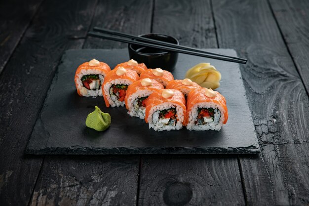 Japanese cuisine rolls on a square plate on a black table