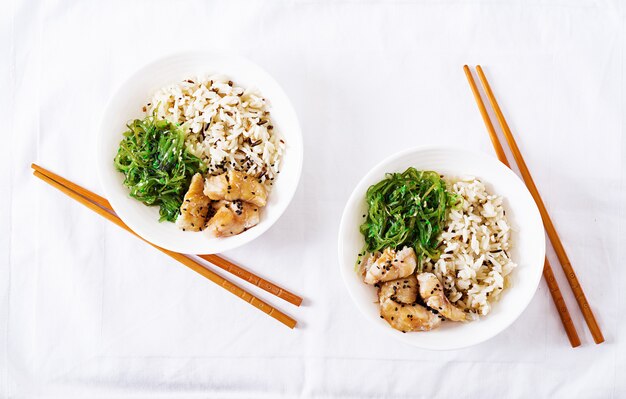 Japanese food. Bowl of rice, boiled white fish and wakame chuka or seaweed salad.  Top view. Flat lay