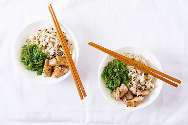 Japanese food. Bowl of rice, boiled white fish and wakame chuka or seaweed salad.  Top view. Flat lay