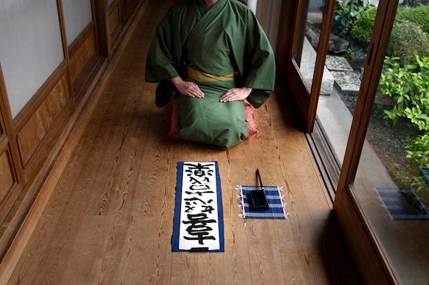 Uomo giapponese che si rilassa scrivendo a mano su un foglio Foto Gratuite