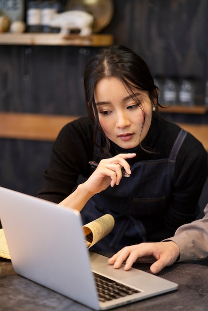 Uomo e donna giapponesi che lavorano utilizzando un computer portatile in un ristorante