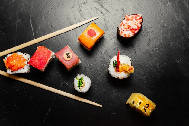 Японские суши и палочки для еды на черном фоне. Суши-роллы, нигири, маки