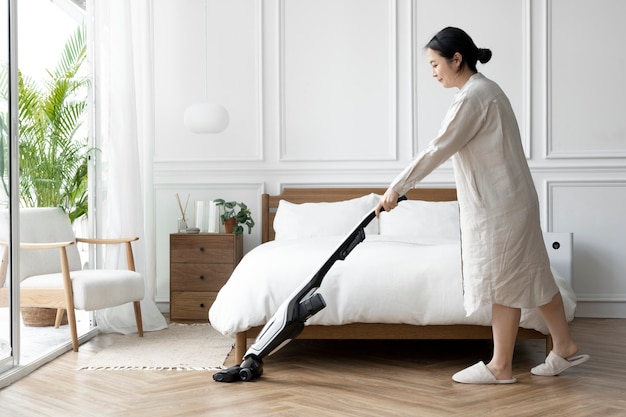 그녀의 침실을 진공 청소기로 청소하는 일본 여성