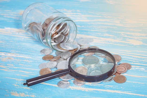 Jar of coins and a magnifying glass on the table