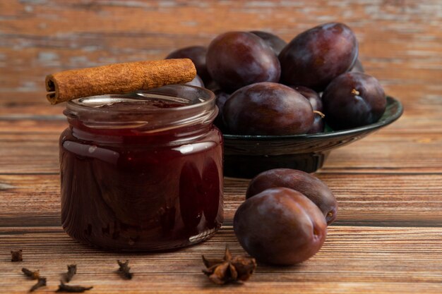 A jar of confiture with plums around.