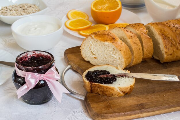 Jar of currant jam on table with loaf of bread