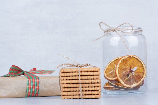 Jar of dried orange and biscuits on marble background. 