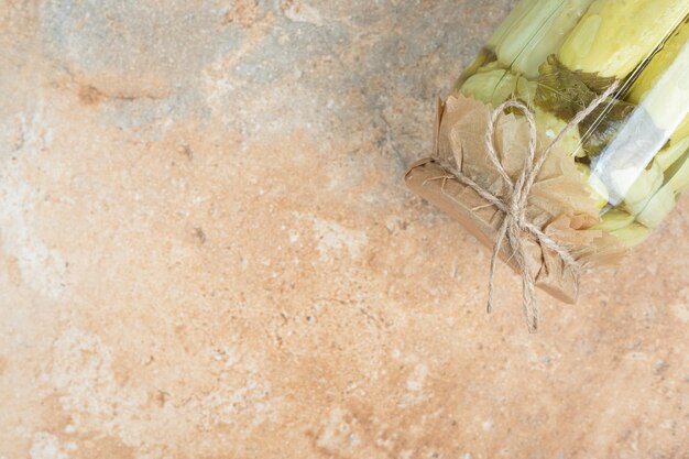 Un barattolo di cetrioli sottaceto fatti in casa sulla superficie di marmo