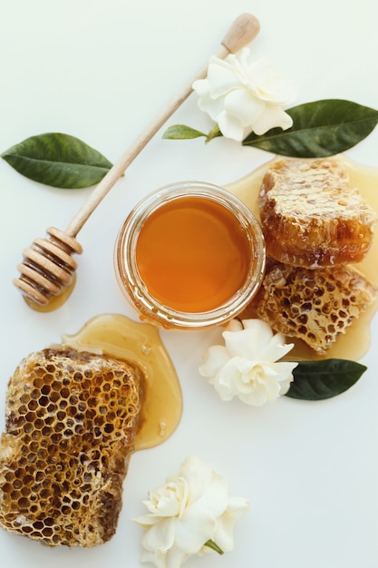 A jar of honey with flowers around