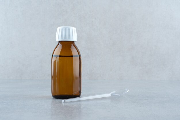 A jar of medicine drink with plastic spoon