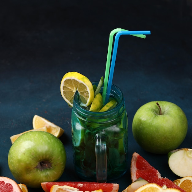 A jar of mojito with sliced and whole fruits.