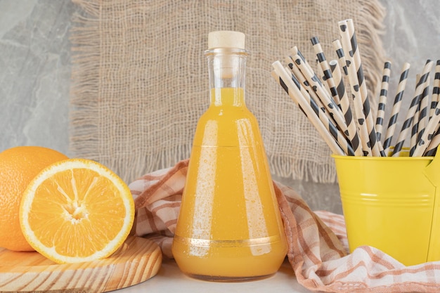 Jar of orange juice with fresh oranges on marble surface