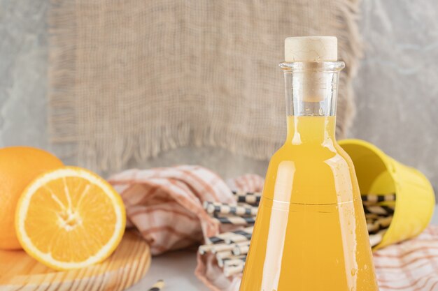 Jar of orange juice with fresh oranges on marble surface