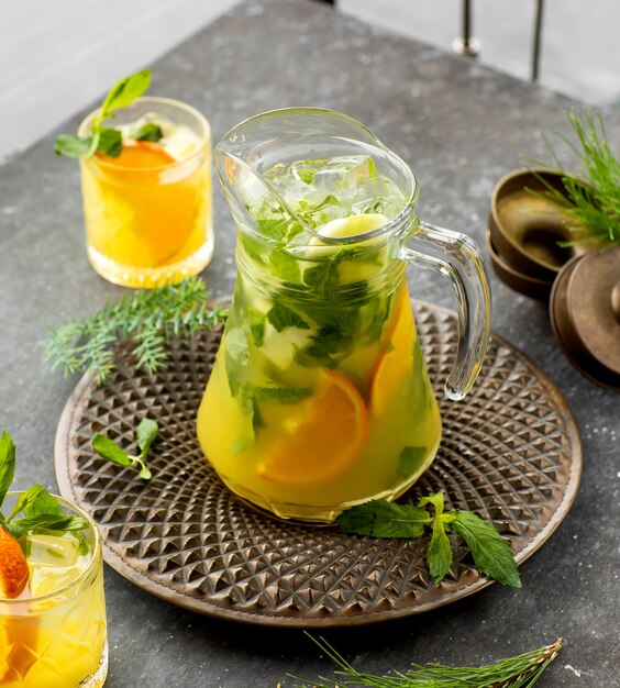 A jar of orange mojito drink placed in bronze plate