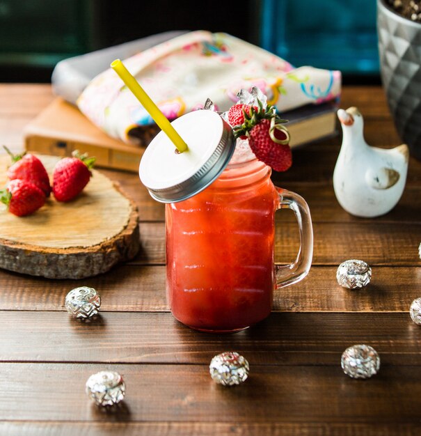 A jar of strawberry smoothie with ice cubes.