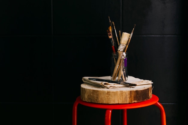 Jar with brushes near black wall