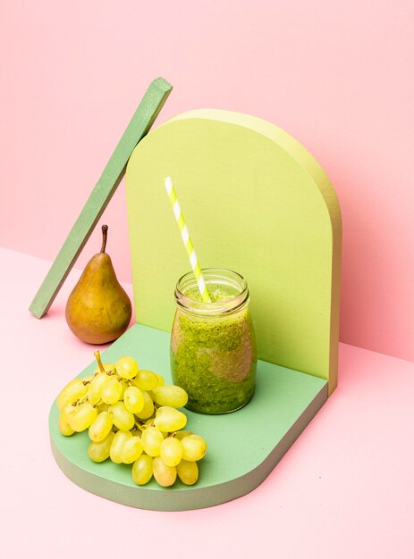 Jar with fresh smoothie of pear and grapes on desk