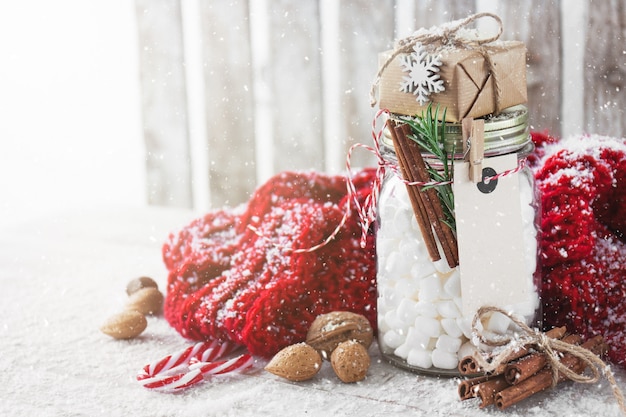 Jar with marshmallow and small gift with christmas decorations,