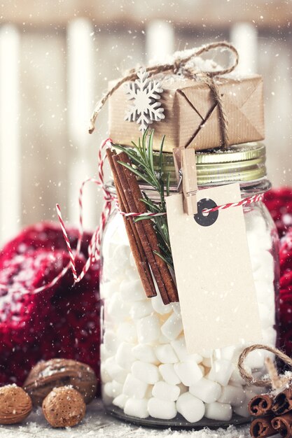 Jar with marshmallow and small gift with christmas decorations,