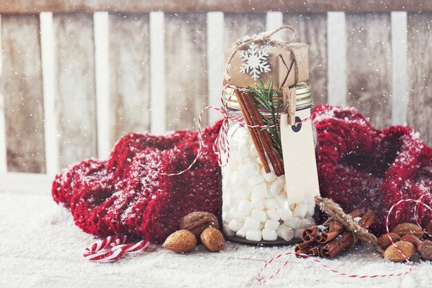 Jar with marshmallow and small gift with christmas decorations,