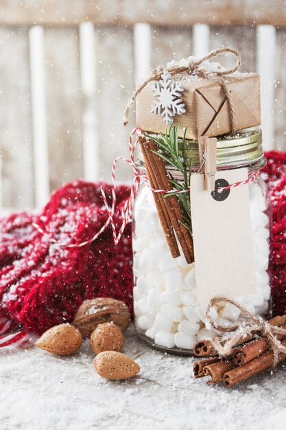 Jar with marshmallow and small gift with christmas decorations,