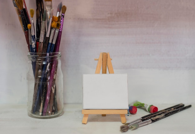 Free photo jar with painting brushes and canvas