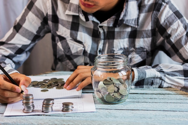 Jar with savings coins on table