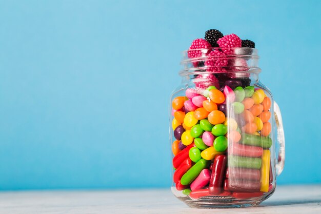 Jar with sweets on blue background