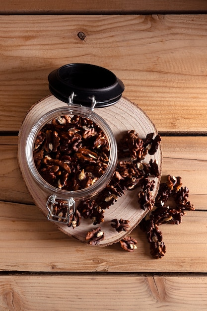 Jar with walnuts on wooden board, top view