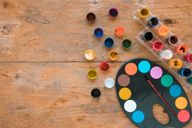 Jars of gouache and palette with paint brush