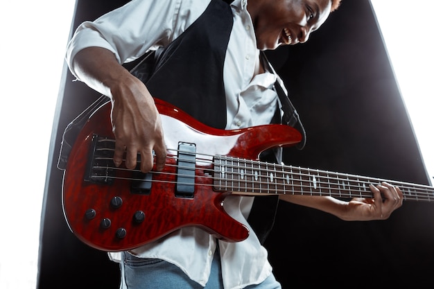 Jazz musician playing bass guitar in the studio on a black wall