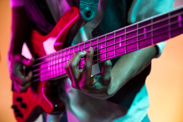 Jazz musician playing bass guitar in the studio on a neon wall