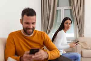 Free photo jealous suspicious mad wife arguing with obsessed husband holding phone texting cheating on cellphone distrustful girlfriend annoyed with boyfriend mobile addiction distrust social media dependence