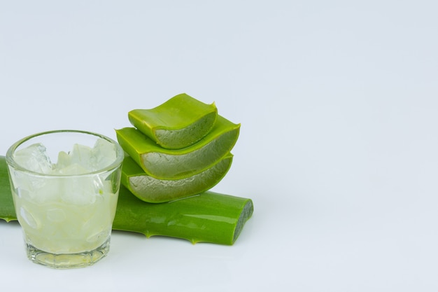 Jel of aloe vera in a glass with aloe vera leave is near together on white wall.