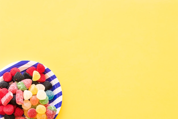 Jelly candies on striped plate over the yellow background