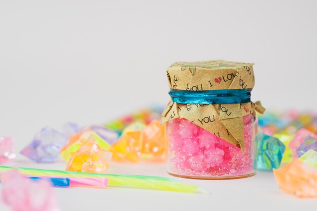 Jelly candle wax in bottle with colorful beads on white background
