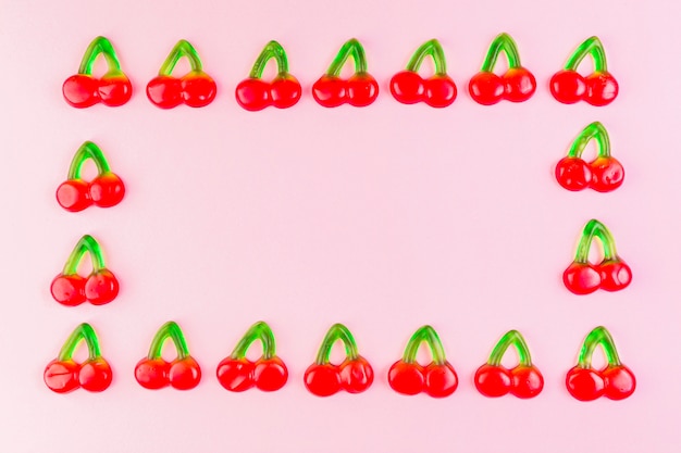 Jelly cherry candies forming rectangular shape frame on pink backdrop