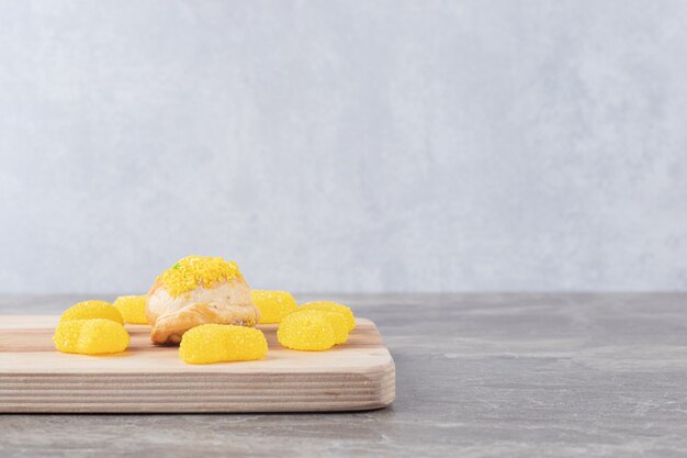 대리석 표면에 레몬 맛 분말 토핑을 얹은 작은 롤빵 주위에 젤리 과자
