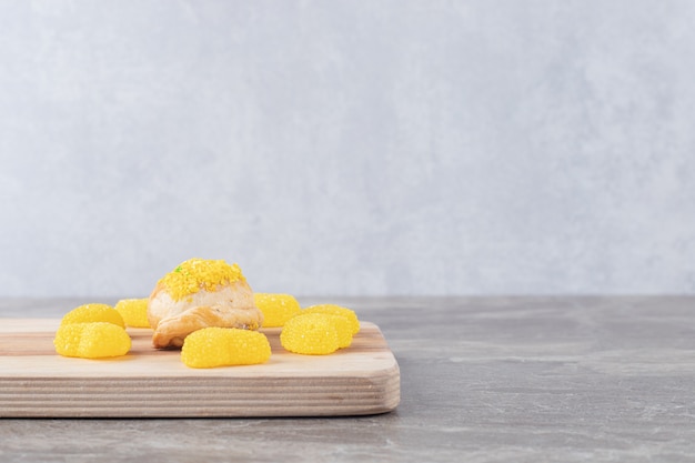 jelly sweets around a small bun with lemon flavored powder topping on marble surface