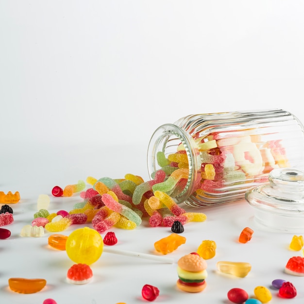 Jelly worms spilled from jar near candies