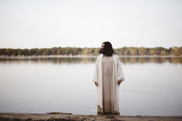 Jesus Christ standing in the water near the shore while looking in the distance