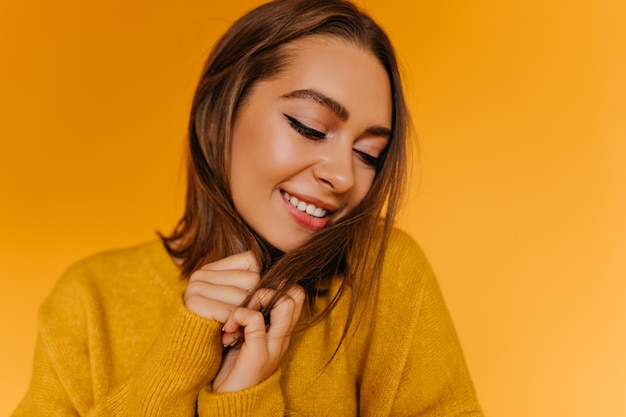 Jocund female model in sweater laughing with eyes closed.