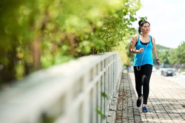 Free photo jogging girl running outdoors with earphones listening to music