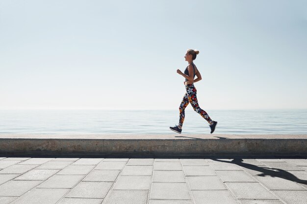 海岸を走っている若い女性のジョギング